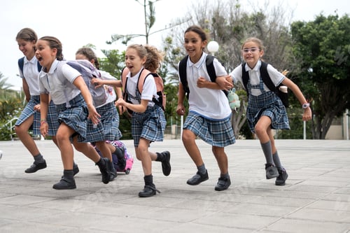 Preview: Excited elementary school girls running together in the school courtyard before class