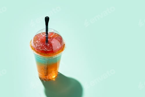 Preview: Colorful frozen slush drink with straw and hard sunlight on pastel background