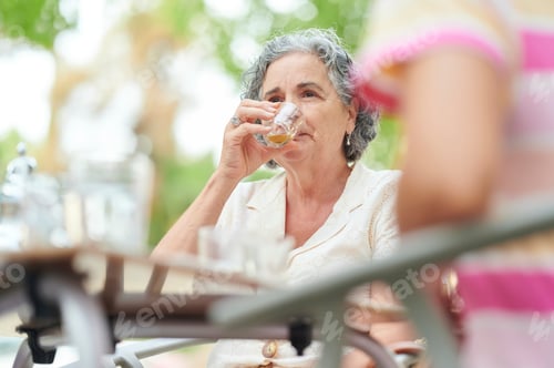 Preview: Senior woman drinking tea with family outdoors