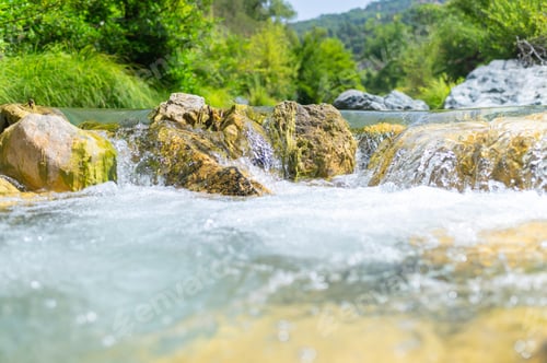 Preview: Clear river water flowing over mossy rocks