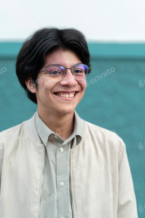 Preview: Portrait of young Latino man in front of green wall on the street