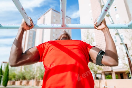 Preview: Athlete doing pull-ups on horizontal bar in urban environment
