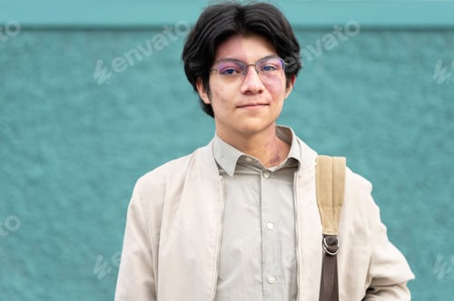 Preview: Portrait of young Latino man in front of green wall on the street
