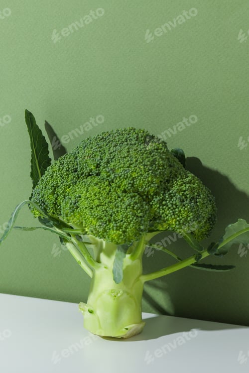 Preview: Broccoli sits on a surface in front of a plain green wall