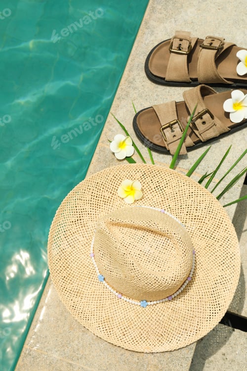 Preview: A straw hat and sandals are next to a pool with flowers