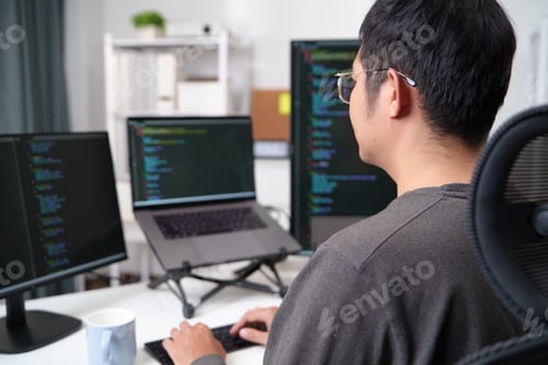 Focused Programmer Working on Code with Multiple Monitors in an Office Setup