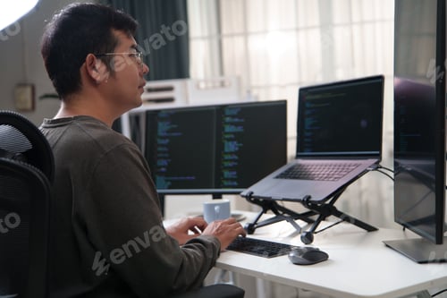 Preview: Focused Developer Working on Code with Multiple Computer Screens in a Tech Environment