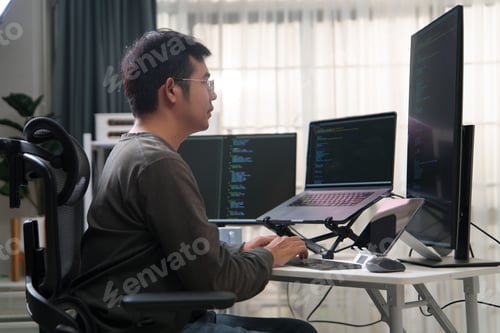 Preview: Focused Developer Engaged in Programming Tasks with Multiple Screens Displaying Code