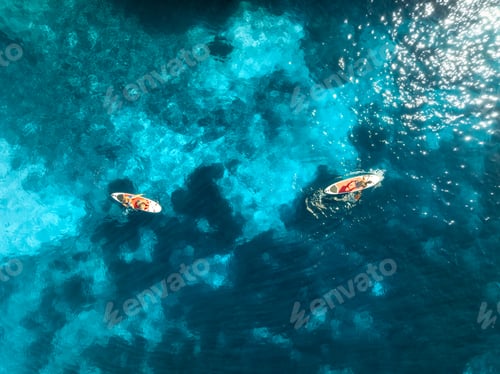 Preview: Aerial view of people on sup boards in crystal clear blue sea