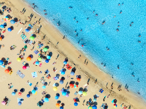 Preview: Aerial view of colorful umbrellas on sandy beach, swimming people