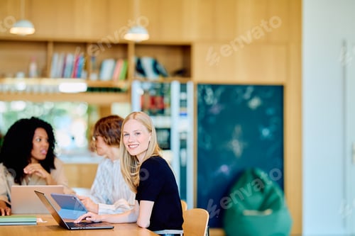 Preview: Happy woman working on laptop in modern office