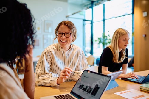 Preview: Smiling businesswomen collaborating working in modern office environment