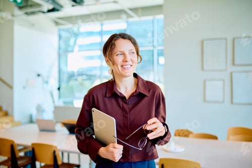 Preview: Professional woman holding tablet and glasses in modern office
