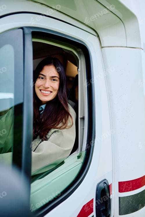 Preview: Happy woman smiling from motorhome on road trip