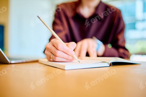Preview: Person taking notes in notebook planning strategy