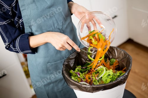 Preview: Woman Dumping Fried Potato Wedges From a Plate Into a Trash Bin