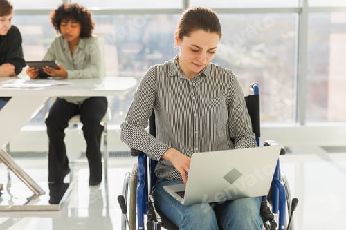 Preview: Accessible environment. Woman in chair for people with disability working with laptop in modern offi
