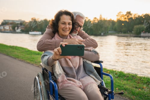 Preview: Senior couple woman in wheelchair caregiver old man making selfie enjoying walking. Elderly family m
