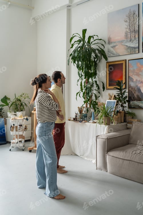 Preview: Creative family husband and wife look at wall with paintings exhibition in home gallery workshop.