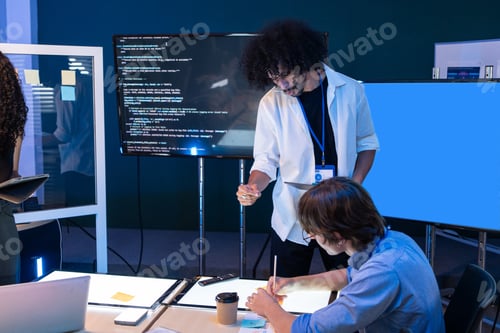 Preview: Developers discussing computer code on a screen during a technical meeting