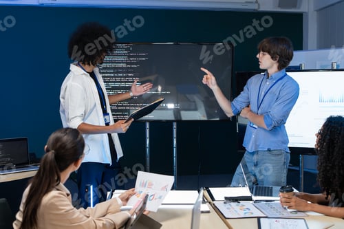 Preview: Code developer explaining program on the screen to team at the meeting
