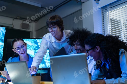 Preview: Tech team reviewing project on laptop at the office at night