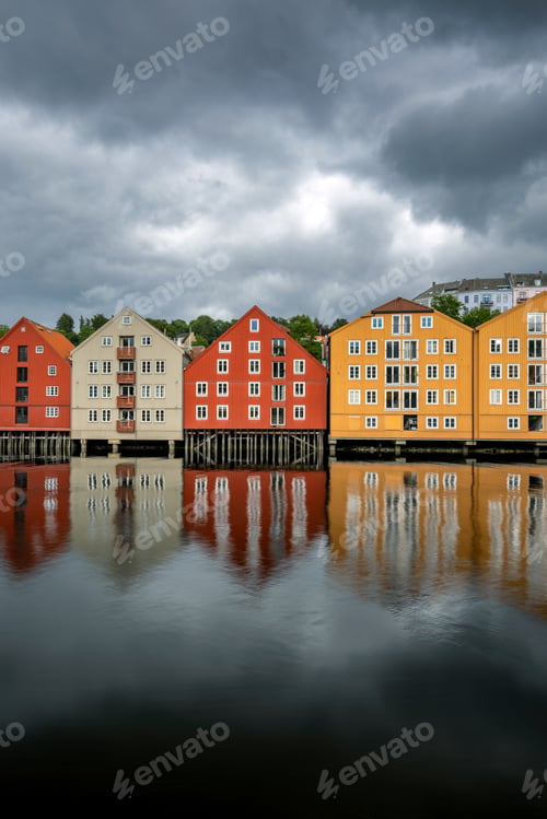Preview: Colorful Wooden Houses Reflected in Calm River Under Dramatic Sky