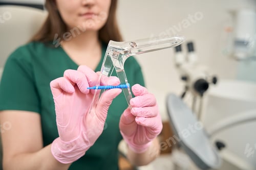 Preview: Adult woman in medical examination room holding swab and speculum