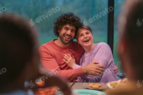 Preview: Joyful couple embracing during family dinner party
