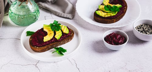 Preview: Beetroot hummus and avocado on rye bread on a plate on the table web banner