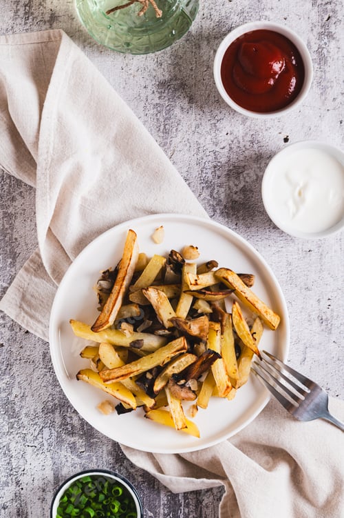 Preview: Crispy French fries served with mushrooms on a plate on the table top and vertical view