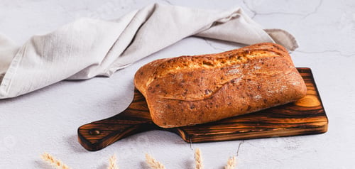 Preview: Fresh baked ciabatta loaf bread on a cutting board on the table web banner