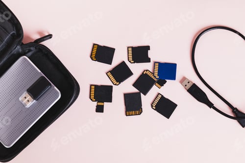 Preview: A set of flash drives, a hard drive in a case on a pink background top view