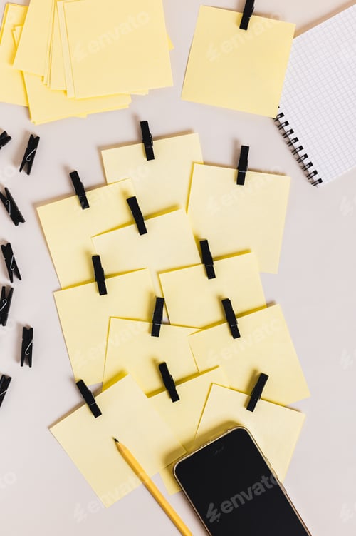 Preview: A pile of identical notepads, a smartphone, a notebook, and a pencil on the table top and vertical v