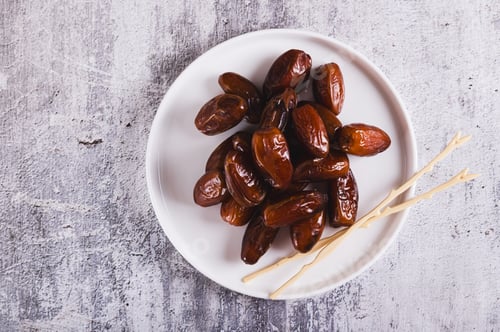 Preview: Close up of sweet dates on a plate and sticks on the table top view