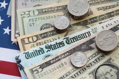 Preview: American US dollars money bills and coins with stimulus bill or refund check on American flag