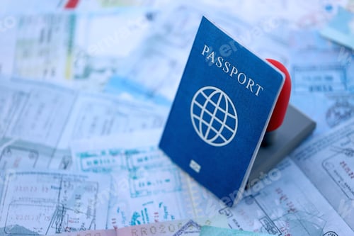 Preview: Border crossing stamp on passport pages full of colorful stamps after travel and tourism