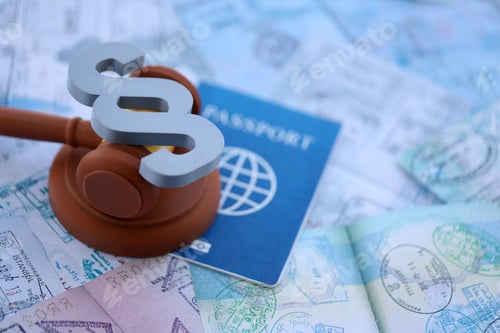Preview: Judgement gavel and paragraph symbol on passport pages full of colorful stamps after travel