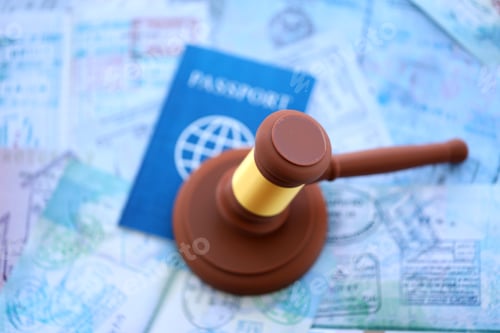 Preview: Judgement gavel on passport pages full of colorful stamps after travel and tourism