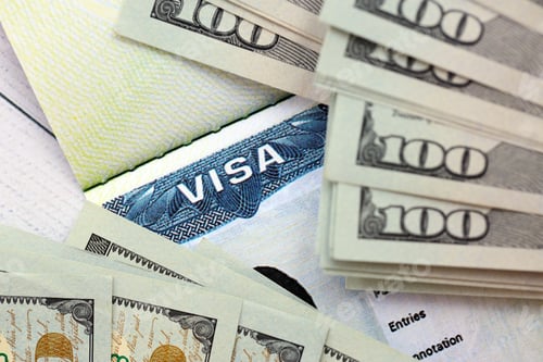 Preview: US visa sticker seen in passport and dollar banknotes placed on top. Concept for immigration