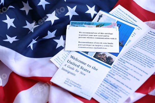 Preview: Permanent resident green card in envelope and guide for new immigrants lies on US flag