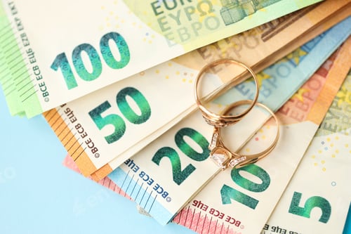 Preview: European union Euro money bills and coins with wedding rings on blue table