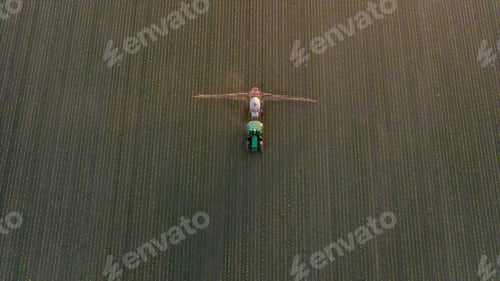 Preview: NOT AI! - Aerial view of crop sprayer working on a corn field at sunset.
