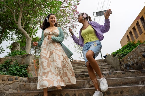 Preview: Young women friends enjoying music walking actively outdoors