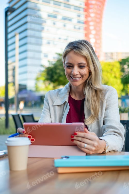 Preview: Businesswoman smiling using digital tablet at outdoor cafe