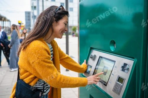 Preview: Woman buying public transport ticket from an outdoor machine