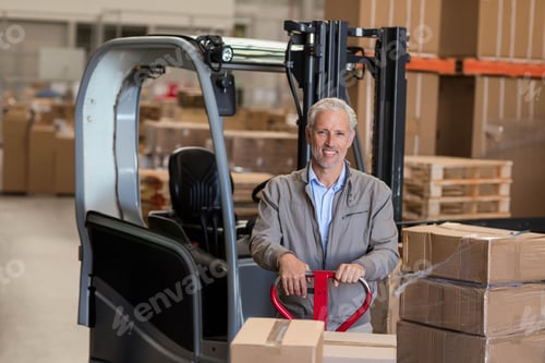 Preview: Mature man standing at red pallet jack in warehouse, moving stacked boxes wrapped with stretch film
