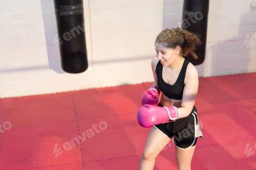 Preview: Teenage girl in sportswear holding guard and stepping on red mats with pink gloves, copy space