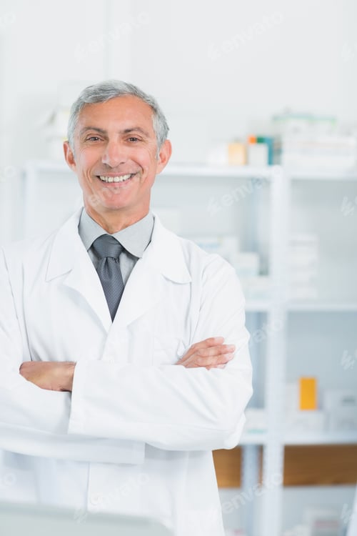 Preview: Senior male medical professional standing arms crossed wearing lab coat at clinical shelving