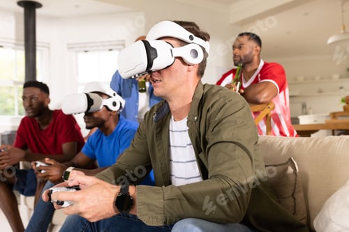 Preview: Male friends playing virtual reality games in living room with white headsets and controllers